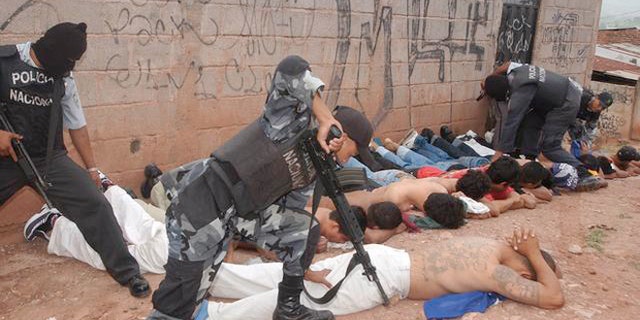 Police officers detain members of the Mara 18 and MS 13 gangs during the tour of President Ricardo Maduro and Security Minister Oscar Alvarez to the Colonia Bellavista neighborhood in Tegucigalpa, Honduras, Wednesday, July 2, 2003. The president sent a law to Congress on Tuesday, prohibiting gangs in the country.(AP Photo/Antonio Romero)