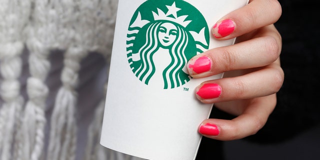 A woman holds a Starbucks takeaway cup in London October 24, 2012. Starbucks's reputation among consumers in Britain has been hit by wave of criticism of its tax affairs from politicians and the media, pollster YouGov said. REUTERS/Suzanne Plunkett (BRITAIN - Tags: BUSINESS FOOD) - RTR39IQG