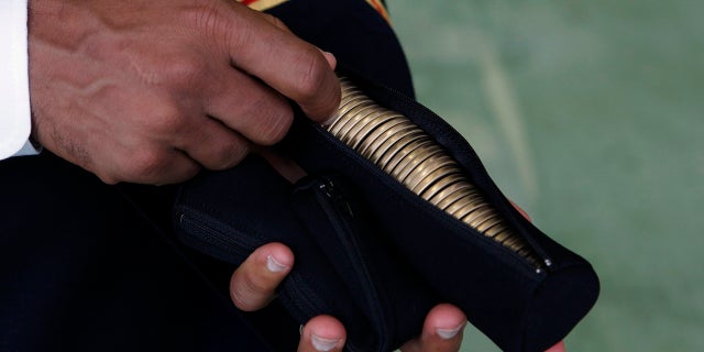 A U.S. Army officer holds a zippered pouch with "Challenge Coins" for Secretary of Defense Leon Panetta to hand out to U.S. military personnel stationed at Yokota Air Base in Japan, Sept. 17, 2012.