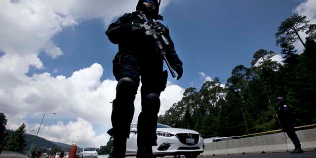 Federal Police patrol a checkpoint west of Mexico City, Thursday, July 16, 2015. A widespread manhunt that included highway checkpoints, stepped up border security and closure of an international airport failed to turn up any trace of drug lord Joaquin "El Chapo" Guzman after he escaped through an underground tunnel in his prison cell. (AP Photo/Marco Ugarte)