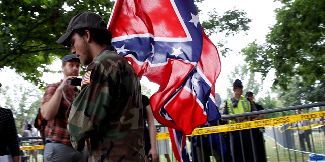 A white supremacists carries the Confederate flag as he arrives for a rally in Charlottesville, Virginia, U.S., August 12, 2017. REUTERS/Joshua Roberts - RTS1BI7C