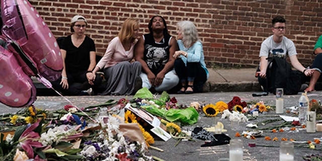 Women sit by an impromptu memorial of flowers commemorating the victims at the scene of the car attack on a group of counter-protesters during the "Unite the Right" rally as people continue to react to the weekend violence in Charlottesville, Virginia, August 14, 2017. REUTERS/Justin Ide     TPX IMAGES OF THE DAY - RTS1BTBR