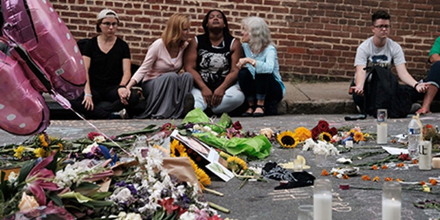 Women sit by an impromptu memorial of flowers commemorating the victims at the scene of the car attack on a group of counter-protesters during the "Unite the Right" rally as people continue to react to the weekend violence in Charlottesville, Virginia, August 14, 2017. REUTERS/Justin Ide TPX IMAGES OF THE DAY - RTS1BTBR