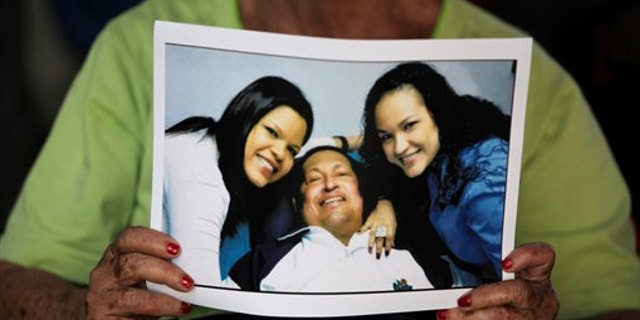 Feb. 15, 2013: A woman holds a newly purchased copy of a photo released by the government, showing Venezuela's President Hugo Chavez with two of his daughters, in Caracas,Venezuela.