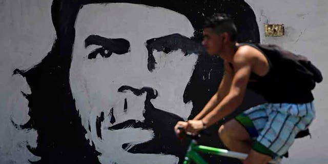 A man cycles beside a mural with the image of Cuban revolution leader Che Guevara in Havana, Cuba.