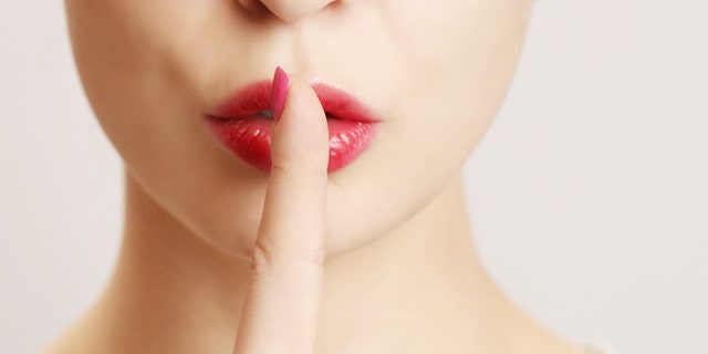 Woman holding her finger to her lips in a gesture for silence.