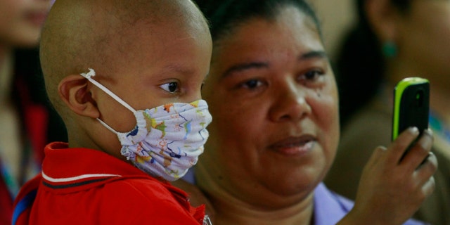 Antonio Ojeda, 3, looks at a cellular phone while receiving chemotherapy treatment at a pediatric hospital.