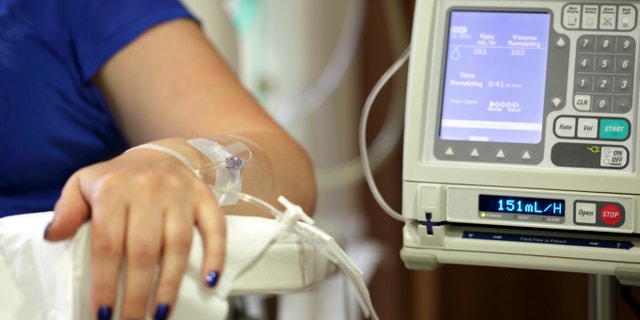 Infusion pump feeding IV drip into patients arm focus on needle