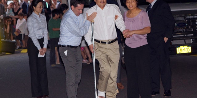 Blind Chinese dissident Chen Guangcheng (C) is helped by his wife Yuan Weijing (R) after arriving in New York May 19, 2012