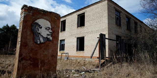 A panel with a portrait of Soviet state founder Vladimir Lenin and an abandoned building are seen at the exclusion zone around the Chernobyl nuclear reactor in the abandoned village of Orevichi, Belarus, March 12, 2016.