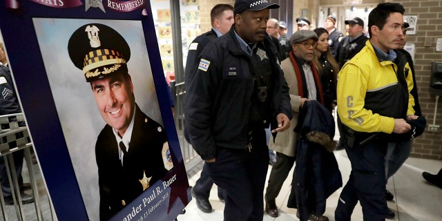 Chicago police officers pass a memorial portrait of Cmdr. Paul Bauer outside the Near North District headquarters, Feb. 14, 2018.