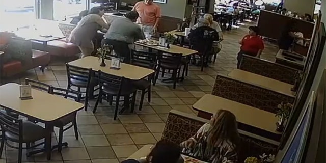 Harris, in gray, with his back to the security camera, rushed to the man's aid after a fellow employee alerted him to the situation in the dining area.