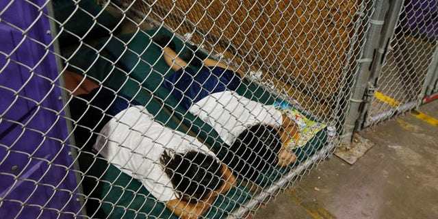 Two female detainees sleep in a holding cell, as the children are separated by age group and gender, as hundreds of mostly Central American immigrant children are being processed and held at the U.S. Customs and Border Protection (CBP) Nogales Placement Center in Nogales, Arizona, June 18, 2014.