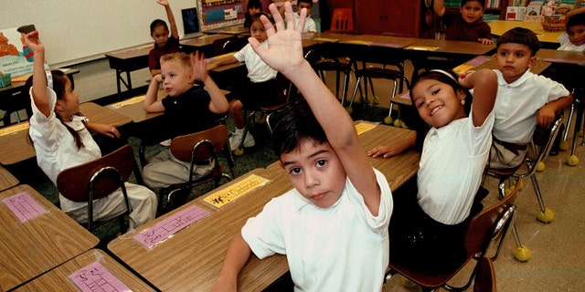 TYLER,TX - SEPTEMBER 11: Monolingual Hispanic students raise their hands to answer a question during a class taught in Spanish at Birdwell Elementary School September 11, 2003 in Tyler, Texas. The first grade students spend half their school day learning reading, writing, and arithmetic in Spanish and the other half learning them in English. Birdwell, a school of 600 students, 60 percent of them Hispanic with a significant portion of them Spanish speakers, requires a dual-language curriculum for it?s kindergarten and first graders. (Photo by Mario Villafuerte/Getty Images)