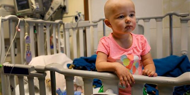 In this June 11, 2015 photo,Talia Pisano stands in her bed at Lurie Children's Hospital in Chicago. Talia is getting tough treatment for kidney cancer that spread to her brain. She's also getting a chance at having babies of her own someday. (AP Photo/Christian K. Lee)