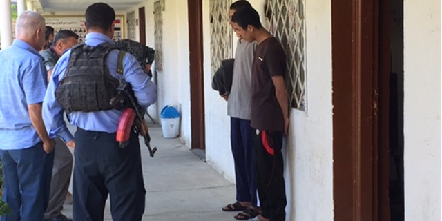 Mostafa Qais Ahmed Dawood and Awad Arkan Helal Mohammed stand solemnly outside following their interrogation.