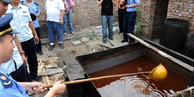 Police inspect illegal cooking oil, better known as "sewer oil" seized during a crackdown in Beijing.