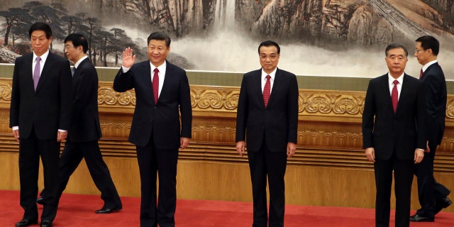 In this Oct 25, 2017, file photo, Chinese President Xi Jinping, third from left, waves near Chinese Premier Li Keqiang, third from right, as they walk in with other members of the Chinese Politburo Beijing's at the Great Hall of the People.
