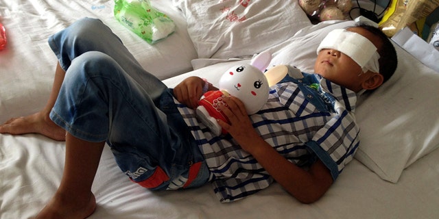 Aug. 28, 2013: In this file photo, Guo Bin lies on a bed in a hospital as he recuperates from an attack in the rural area of Linfen city that left him blind, in Taiyuan in northwest China's Shanxi province. The official Xinhua News Agency said police in northern China suspect that the woman who gouged out the 6-year-old boy's eyes was his aunt who later killed herself by jumping into a well.