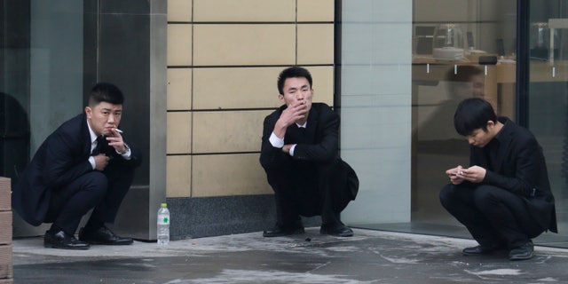 Employees smoke outside an office building in Beijing, November 25, 2014. REUTERS/Jason Lee