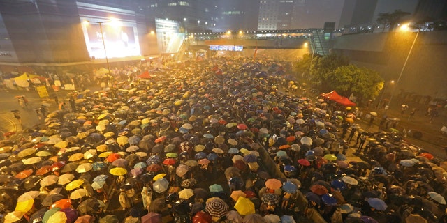 Pro-democracy protesters hold umbrellas under heavy rain in a main street near the government headquarters in Hong Kong late Tuesday, Sept. 30.