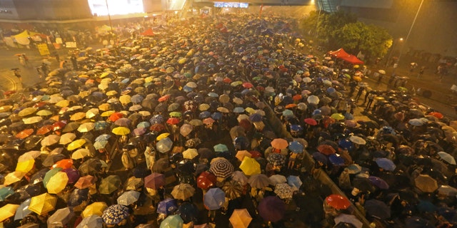 Pro-democracy protesters hold umbrellas under heavy rain in a main street near the government headquarters in Hong Kong late Tuesday, Sept. 30.