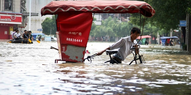 June 20: A Chinese man wades through a flooded street with his tricycle in Lanxi city in east China's Zhejiang province. Heavy rains pounded Zhejiang province over the weekend and the level of a river that passes through Lanxi city has risen sharply. (AP)