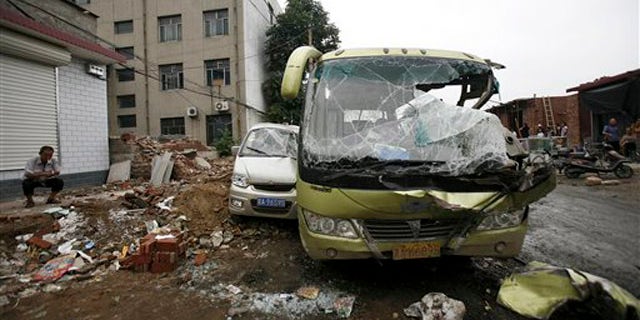 Aug. 1, 2010: Man smokes near smashed vehicles at Yuanshi county, in north China's Hebei province. A drunken shovel loader driver went on a rampage in northern China, smashing into shops and vehicles and killing 11 people, a government spokesman said Monday.
