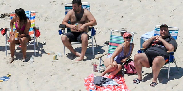 In this Sunday, July 2, 2017, photo, New Jersey Gov. Chris Christie, right, uses the beach with his family and friends at the governor's summer house at Island Beach State Park in New Jersey. Christie is defending his use of the beach, closed to the public during New Jersey's government shutdown, saying he had previously announced his vacation plans and the media had simply "caught a politician keeping his word." (Andrew Mills/NJ Advance Media via AP)