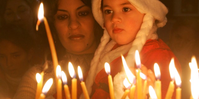 BETHLEHEM, WEST BANK - DECEMBER 24: Iman Haddid and her 2-year-old daughter Dallah light votive candles at the Church of the Nativity December 24, 2004 in the biblical town of Bethlehem in the West Bank. A smaller crowd than in prevous years gathered in Manger Square for the start of the Christmas festivities at the traditional birthplace of Jesus with the local Palestinian governor blaming Israel for not easing security restrictions in time. (Photo by David Silverman/Getty Images)