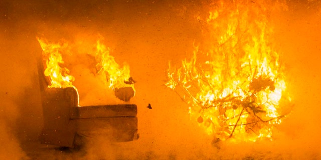 In this Tuesday, Nov. 29, 2016 photo flames engulf the wall and ceiling of a room as well as items in the room thirty-five seconds into the ignition of a Christmas tree during a test burn by the fire protection engineering lab at the Worcester Polytechnic Institute, in Worcester, Mass.