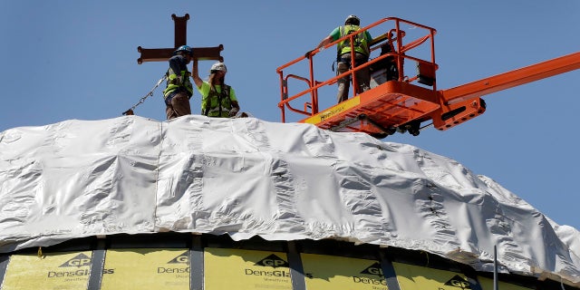 File 2017: Construction workers adjust a temporary cross on the St. Nicholas National Shrine in New York. Work on the Greek Orthodox church destroyed in the Sept. 11 attacks has been stopped amid financial difficulties and questions over how funds have been managed.
