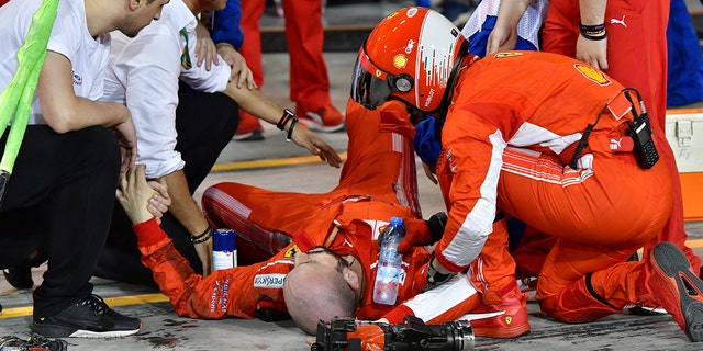 Teammates aid Francesco Cigarini after he was hit by Kimi Raikonnen's F1 car.