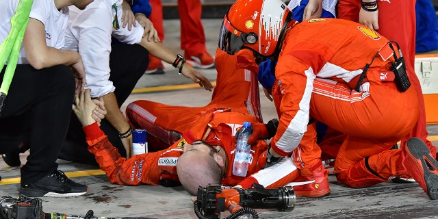 Teammates aid Francesco Cigarini after he was hit by Kimi Raikonnen's F1 car.