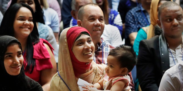 Mosammat Rasheda Akter, center, of Bangladesh, holds her seven-month-old daughter Fahmida during a naturalization ceremony, Tuesday, July 3, 2018, at the New York Public Library's Celeste Bartos Forum.