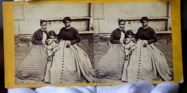 National Park Service curator Kim Robinson holds the photo of Selina Gray, right, who was in charge to care for Arlington House where Gen. Robert E. Lee had lived in for 30 years.