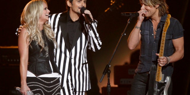 Miranda Lambert, left, Brad Paisley, center, and Keith Urban appear onstage at the 47th annual CMA Awards at Bridgestone Arena on Wednesday, Nov. 6, 2013, in Nashville, Tenn. (Photo by Wade Payne/Invision/AP)