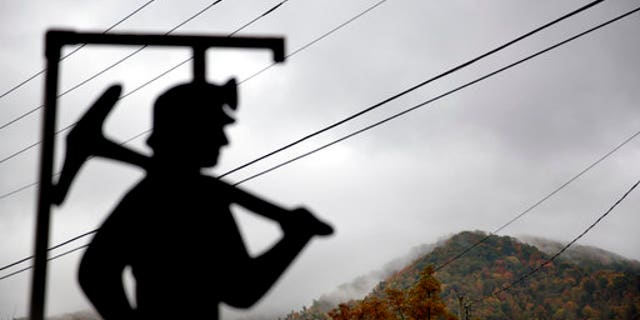 In this Oct. 16, 2014 file photo, fog hovers over a mountaintop as a cutout depicting a coal miner stands at a memorial to local miners killed on the job in Cumberland, Ky.
