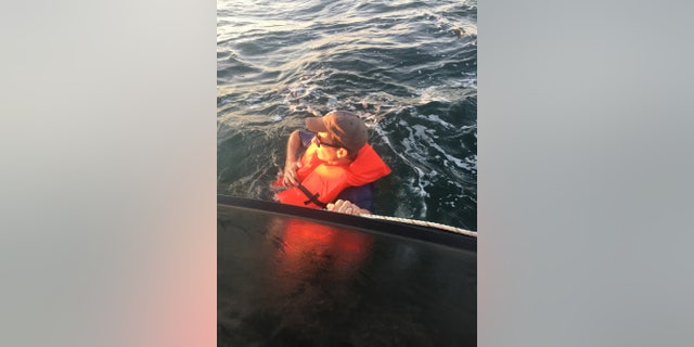 A mariner grasps the side of a 22-foot vessel after the boat capsized near Masonboro Inlet, North Carolina, June 28, 2017