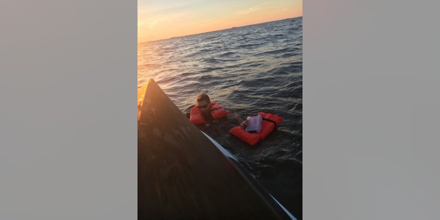 A mariner grasps the side of a 22-foot vessel after the boat capsized near Masonboro Inlet, North Carolina, June 28, 2017.