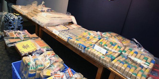A Hong Kong police officer stands by packages of cocaine worth about $77 million which were found at a warehouse in Hong Kong during a news conference Sunday, Sept. 18, 2011.