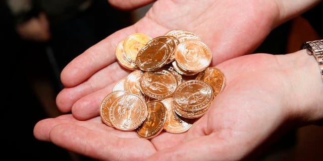 A US Mint worker holds new $1 coins at Grand Central Station in New York February 15, 2007.