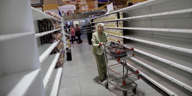 An elderly woman walks through a supermarket in Caracas, Venezuela.