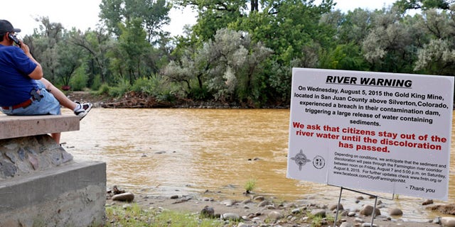 Aug. 8, 2015: A warning sign from the city is displayed in front of the Animas River as orange sludge from a mine spill upstream flows past Berg Park in Farmington, N.M.