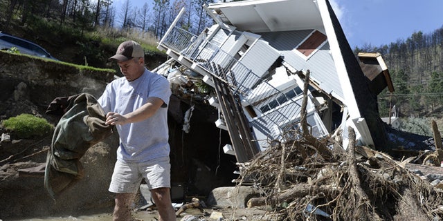 Sept. 19, 2013: In this photo, Sean McCroskey pulls his wife Meg's jacket out of the debris in the river in front of their destroyed home on Gold Run Road in Boulder County, Colo. State highway crews and National Guard troops worked Sunday, Sept. 22, to repair highways to Colorado mountain towns cut off by the unprecedented flooding.