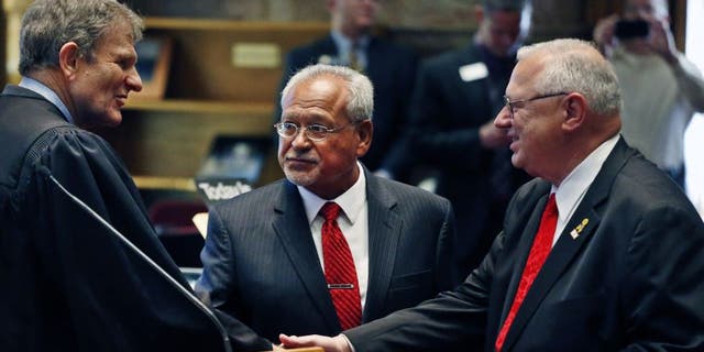 FILE: Oct. 3, 2013: Colorado Supreme Court Chief Justice Michael Bender, left, shakes hands with Republican state senator Bernie Herpin, as state senator George Rivera looks on after the two Republicans were sworn in, having defeated Colorado Democratic senators in a recall over new gun restrictions the previous month