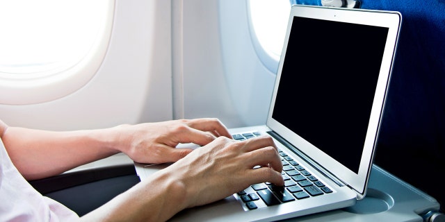 Man using laptop computer on airplane.