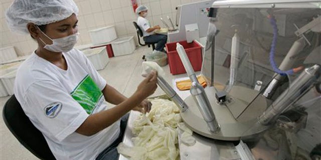 FILE - In this Oct. 30, 2007 file photo, a worker checks rubber condoms at the government-run Natex factory in Xapuri, in Brazil's Amazon. The International Olympic Committee confirmed on May 19, 2016 that three times more condoms will be distributed during the Rio de Janeiro Olympics in 2016 than at the London games four years prior. Part of the large increase is because female condoms will be available for the first time. (AP Photo/Silvia Izquierdo, File)