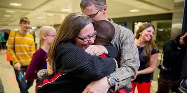 Nov. 11, 2015: Jennifer and Eric Sands of Illinois hug their adopted son Issaac, 12, as he arrives from the Congo at Dulles International Airport.