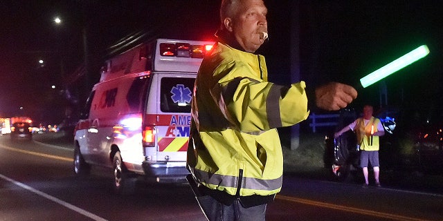A first responder directs traffic as emergency personnel work the scene of an explosion in North Haven, Conn.